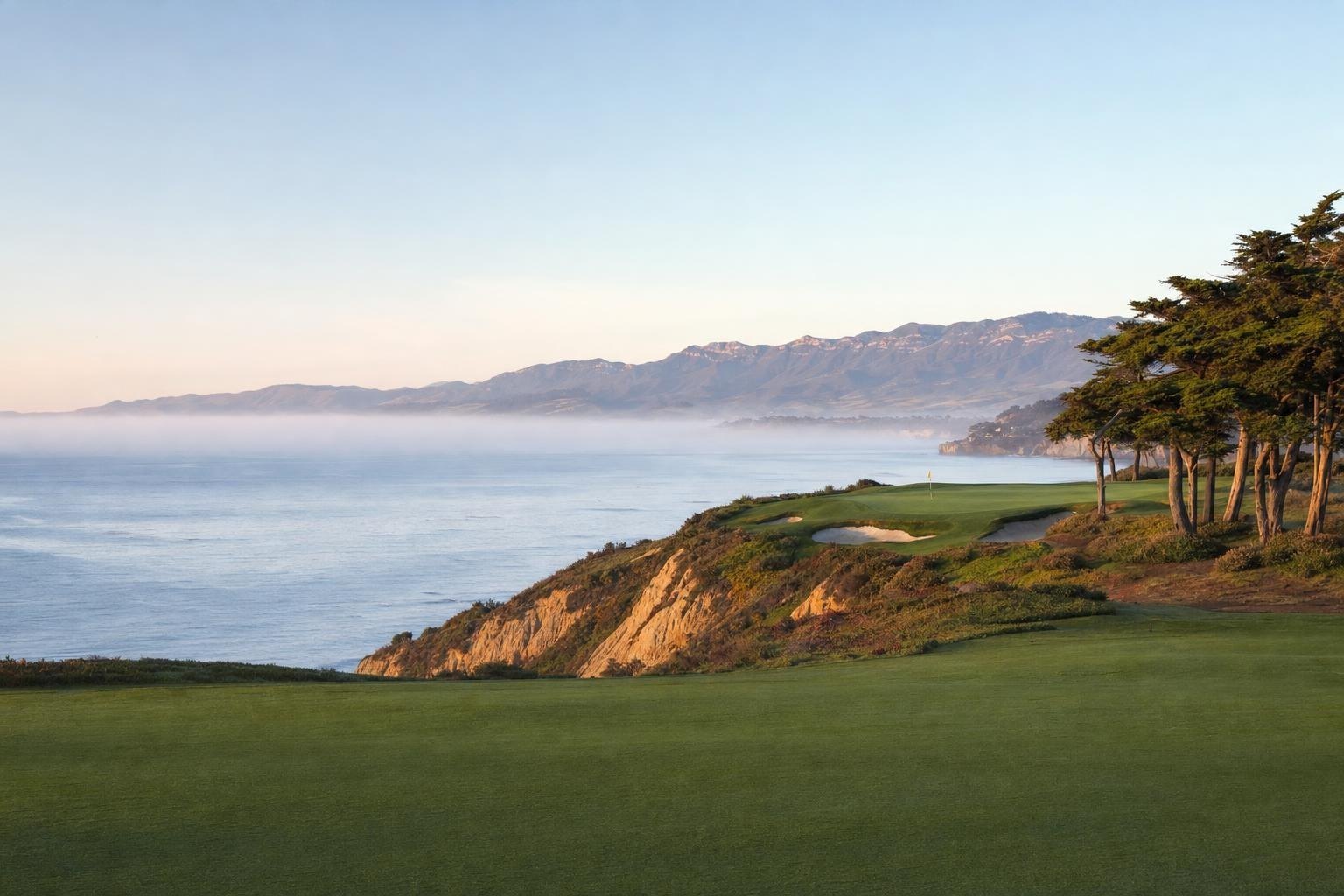 A clifftop golf green above the Pacific near Santa Barbara at dawn, sea mist and the Santa Ynez Mountains behind (AI-generated image)