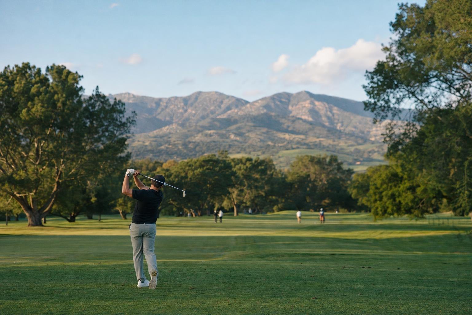 A friendly city golf course with mature trees and the Santa Ynez mountains behind, blue sky (AI-generated image)